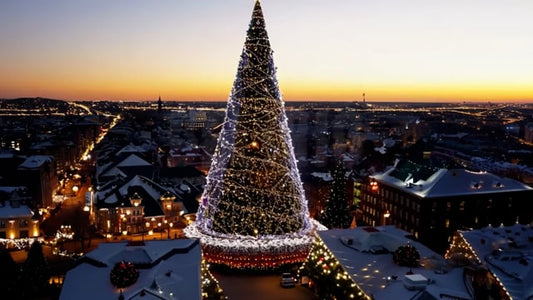 A beautiful aerial view of a city, decorated for Christmas with festive lights and a prominently lit tree in the city center.