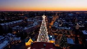 A captivating aerial shot of a city at dusk, bathed in the warm glow of Christmas lights and the twinkling of festive displays.