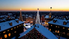 A scenic aerial view of a European village at sunset, with a beautifully lit Christmas tree standing tall amidst the festive holiday glow.