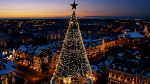 A stunning aerial shot of a Christmas city during sunset, with vibrant holiday lights creating a festive glow over the entire cityscape.