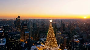 A vibrant aerial view of a city at sunset, with Christmas lights glowing across the city, creating a festive and magical atmosphere.