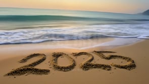 """2025"" written in sand as waves lap at the edges, a peaceful and coastal celebration of the New Year."