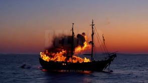 A vessel ablaze in the blue hour ocean scene, with flames consuming the ship as the sky darkens.