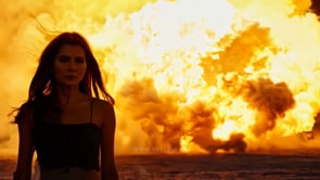 A fearless action hero woman walks confidently away from a giant fireball explosion in a dramatic, cinematic scene.