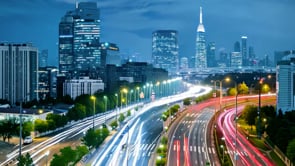 Aerial view showcasing a time-lapse of street lights along an illuminated roadway with vibrant colors and dynamic motion.