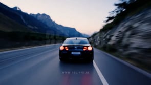 Evening mountain road with blurred car rear lights, creating a serene, defocused background scene.