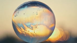 Soap bubble at sunset in a close-up, with ripples and reflections tailored for skincare product promotion.