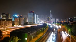 Time-lapse cityscape with busy freeway views, surrounded by skyscrapers illuminated by neon lights.