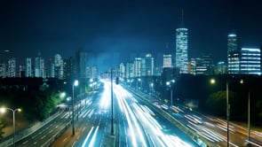 Wide-angle time-lapse of a skyline, showcasing blurred traffic motion and vibrant city light movement.