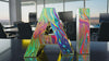 AI letters displaying multi-colored liquid texture against an office environment, blending tech and creativity.