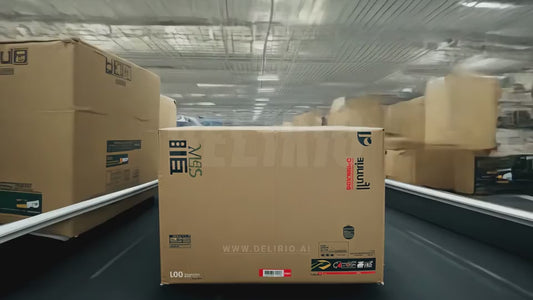 A cardboard box travels through a conveyor belt and along a city street from a first-person perspective.