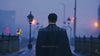 Rear view of a man crossing an ancient bridge in a European city reminiscent of Prague, shrouded in the soft glow of evening fog, evoking a sense of nostalgia and old-world charm.