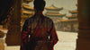 A peaceful over-the-shoulder shot of an East Asian woman in traditional clothing, walking toward a temple, emphasizing cultural heritage and history.